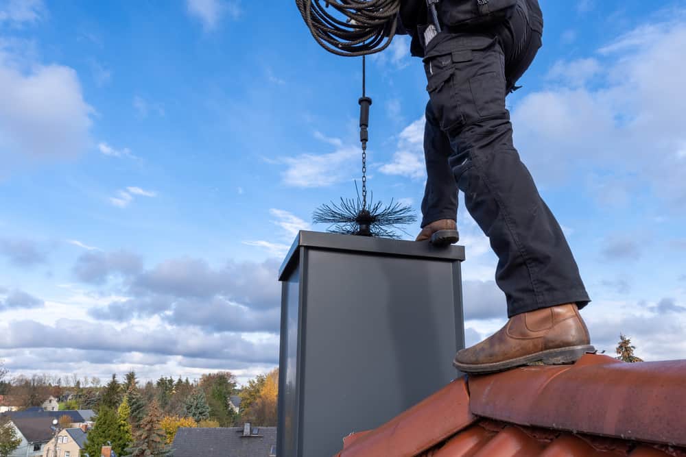 Man cleaning chimney with rope wire brush